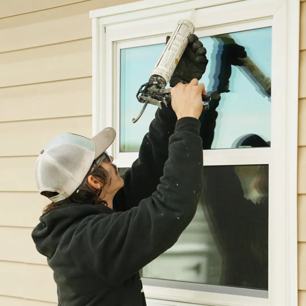 A window installer applying seal on the newly installed window